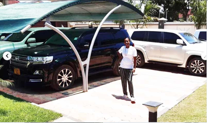 Mama Dangote posing in front of Diamond Platnumz' cars