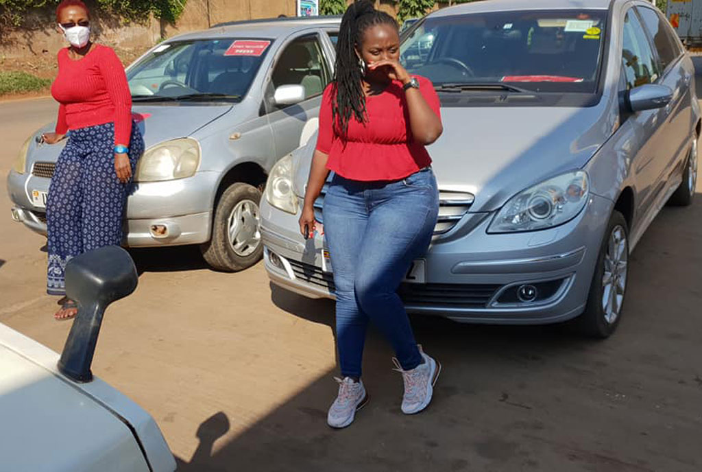 Doreen Nasasira (R) chilling in front of her Mercedes Benz