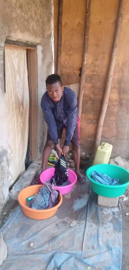 Empra of Muwunya Boys washing clothes at his house