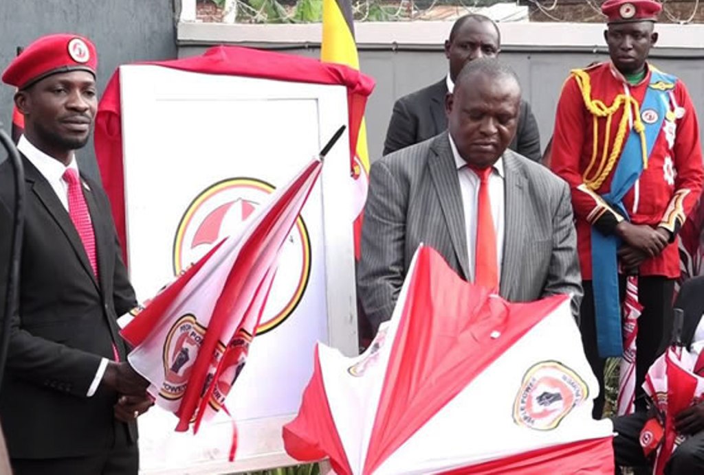Moses Kibalama (R) handing party instruments to Bobi Wine in 2020